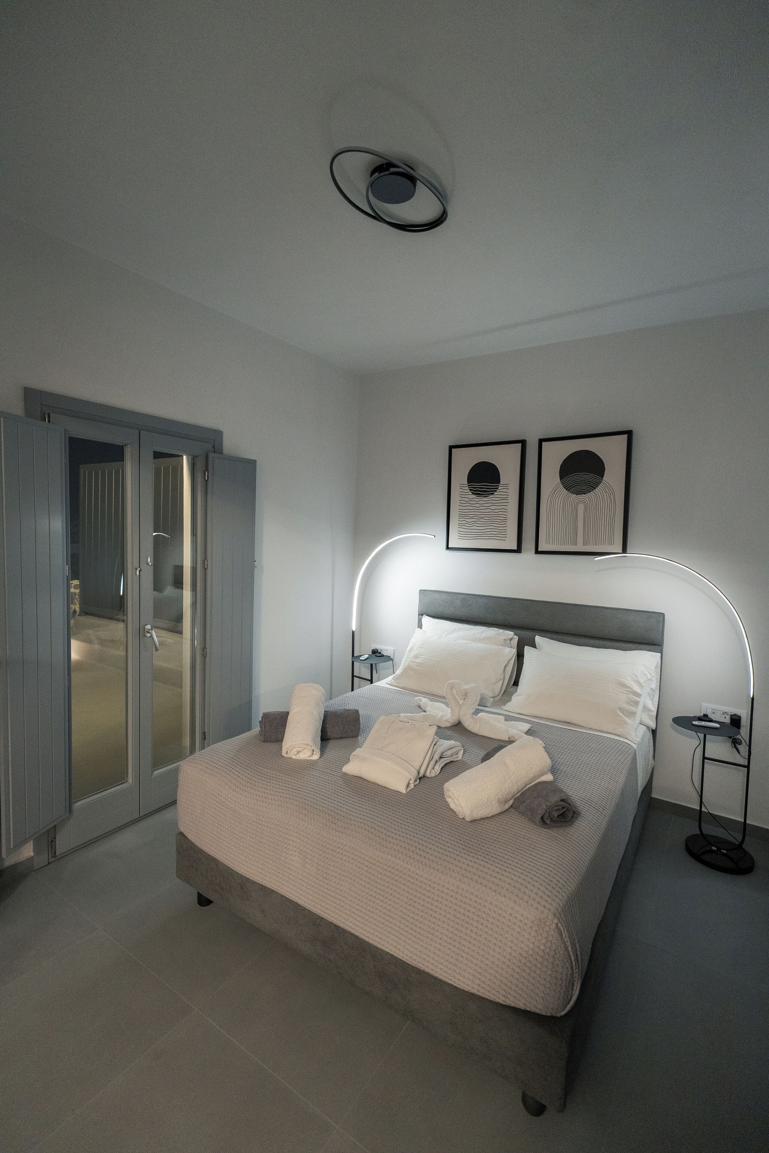 A modern bedroom with a bed, bedside lamps, and a wardrobe.