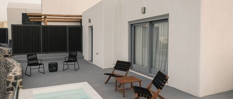 A modern outdoor pool area with a rectangular pool, black lounge chairs, and a stone wall.