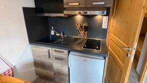 A compact kitchen with a sink, stove, and refrigerator. - Cozy studio in Châtel, near center, with mountain corner, parking and balcony (Châtel)