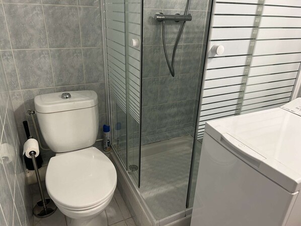 Een badkamer met een toilet, een glazen douchecabine en een wit wastafel.