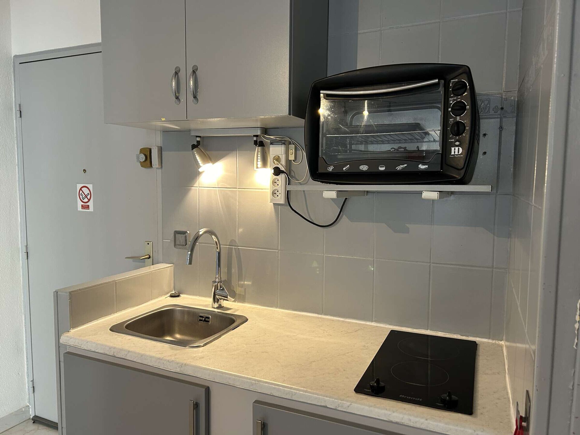 A compact kitchen with a built-in toaster oven, a sink, and a stove.