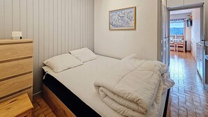 Een slaapkamer met een bed, een houten dressoir en een inlijst kaart aan de muur.