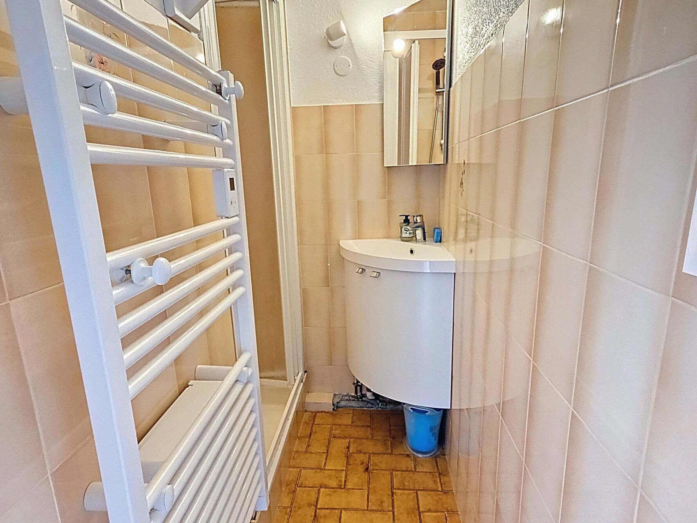 A bathroom with a white radiator, a sink, and a mirror.