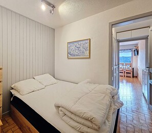 A bedroom with a bed, wooden dresser, and a framed map on the wall.