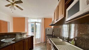 Una cocina con encimeras de granito, armarios de madera, un microondas y un refrigerador.