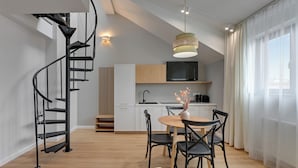 A modern kitchen with a TV, wooden cabinets, and a dining area with a table and chairs. - Waterlane Vintage Fitness & Parking by Downtown Apartments (Gdansk)