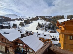 A ski resort with wooden buildings and a snowy mountain backdrop.