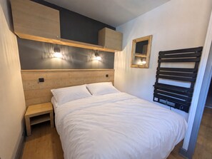 Ein Schlafzimmer mit einem hölzernen Kopfteil, einem Nachttisch und einem Wandregal.