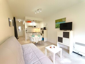 A compact living space with a kitchenette, a dining area, a television, and a sofa. - Cozy studio for 4 with balcony and parking in Saint-Lary-Soulan (Saint-Lary-Soulan)