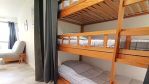 Quarto com beliche, uma pequena mesa e uma cadeira.