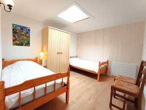 Ein Schlafzimmer mit zwei Holzbett, einem Kleiderschrank, einem Heizkörper und einem Sessel.