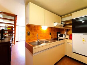 Eine kleine Küche mit Spüle, Mikrowelle und Kühlschrank.