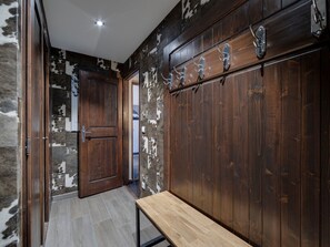 Stylish hallway with a bench and door leading to a cozy room, featuring a unique wood and white patterned wall and metal hooks.