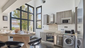 Una cocina moderna con una isla central, electrodomésticos de acero inoxidable y grandes ventanas con vistas al exterior.