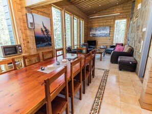 Un interior de madera con una mesa de comedor, sillas, un sofá y un televisor.