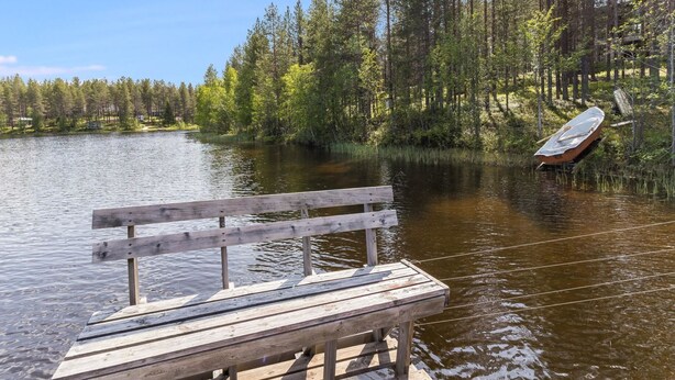 A wooden dock extending into a calm lake surrounded by dense trees.