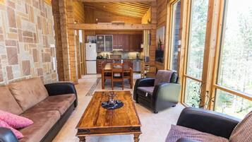 A cozy interior with a stone wall, wooden ceiling, a dining area, and a kitchen.