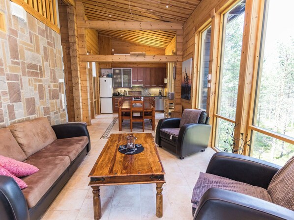 A cozy interior with a stone wall, wooden ceiling, a dining area, and a kitchen.