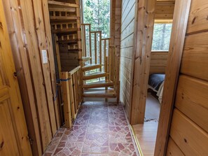 A wooden staircase leading to a room with a bed, a window, and a stone-tiled floor. - Matkajoentie 4b by Interhome (Kuusamo)