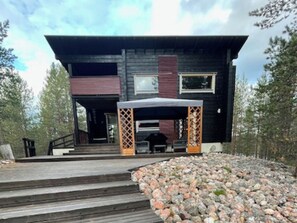 En modern tvåvåningsbyggnad med en träveranda och en stenlagd gångväg som leder till entrén.