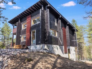 A modern two-story house with a stone foundation, large windows, and a wooden exterior.