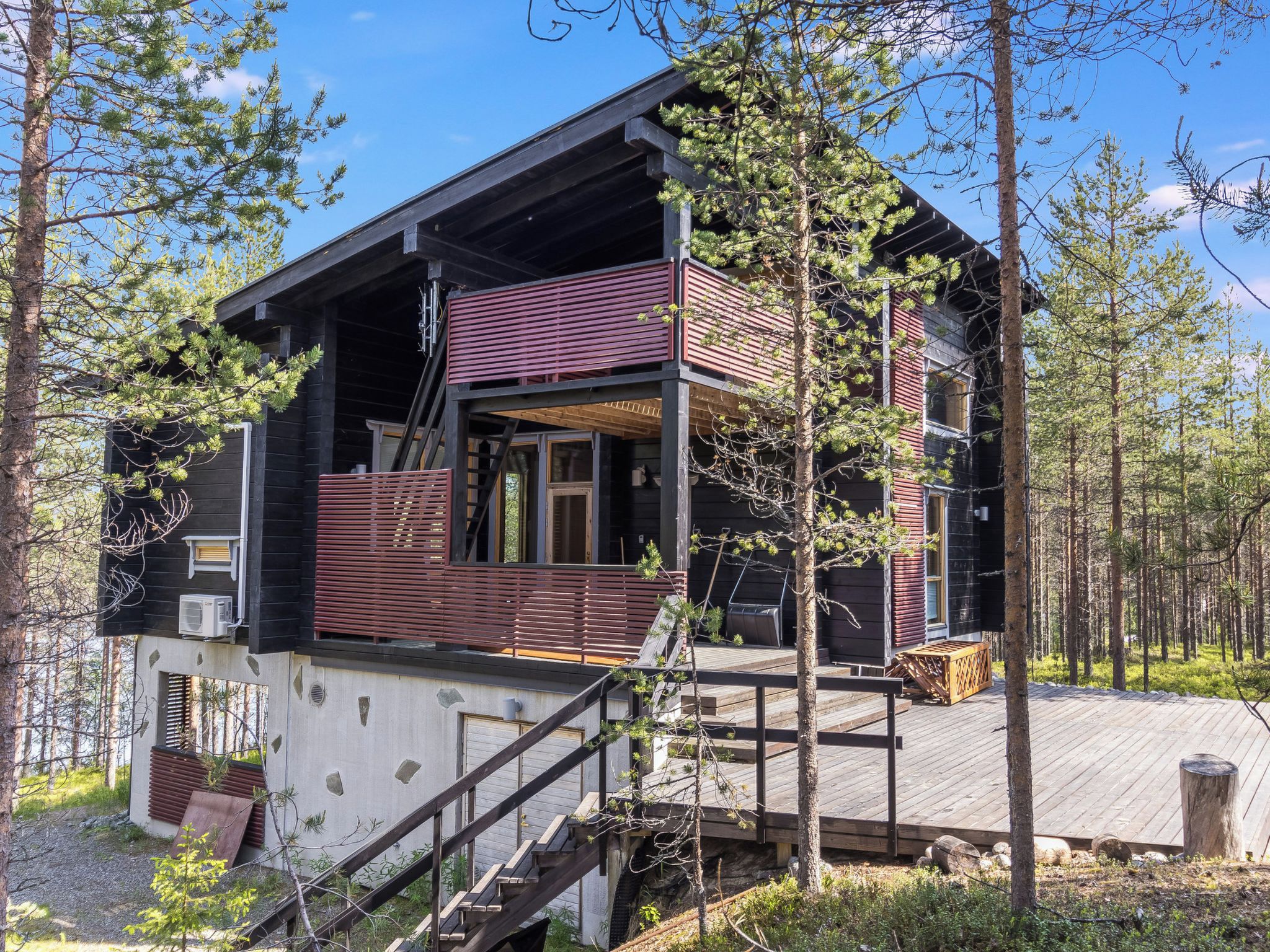 A cabin with a deck, a staircase, and a large window.