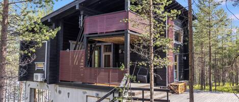 A cabin with a deck, a staircase, and a large window.