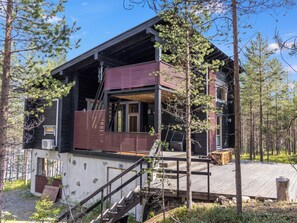 A cabin with a deck, a staircase, and a large window.