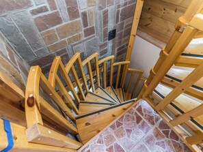 A wooden spiral staircase with a brick wall background.