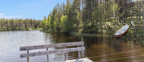 Un muelle de madera se adentra en un lago tranquilo rodeado de un bosque frondoso.