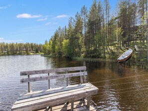Un muelle de madera se adentra en un lago tranquilo rodeado de un bosque frondoso.