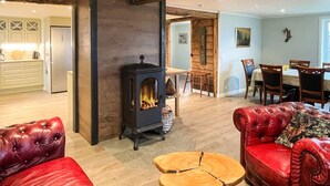 A cozy living room with a fireplace, red leather sofas, and a dining area with wooden chairs. - 4 Star Holiday Home in Karlskrona (Eringsboda)