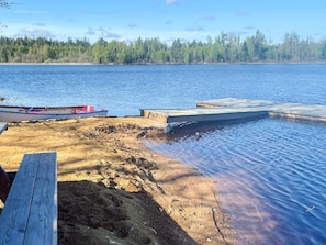 A lakeside dock with a boat, a wooden pier, and a sandy shore. - 4 Star Holiday Home in Karlskrona (Eringsboda)