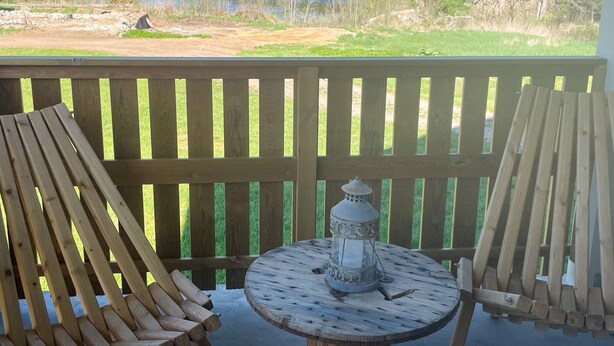 A wooden deck with two Adirondack chairs and a small round table with a lantern. - 4 Star Holiday Home in Karlskrona (Eringsboda)