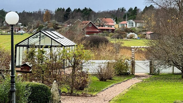 A residential area with a pathway leading to houses, a lamp post, and a greenhouse. - 7 Person Holiday Home in Ellos (Ellos)