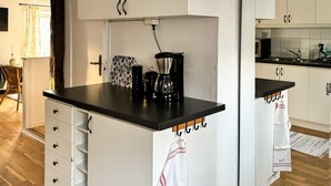 A kitchen with white cabinets, a black countertop, and a coffee maker. - 7 Person Holiday Home in Ellos (Ellos)