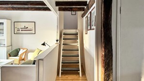 A narrow hallway with a wooden floor, a staircase, a white sofa with cushions, and a framed picture on the wall. - 7 Person Holiday Home in Ellos (Ellos)