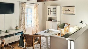 A cozy room with a dining table, wicker chair, white sofa, and a cabinet with glass doors. - 7 Person Holiday Home in Ellos (Ellos)