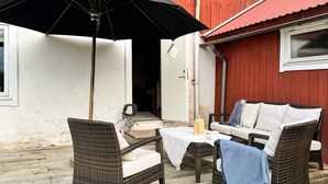 An outdoor seating area with wicker furniture, a table, and an umbrella. - 7 Person Holiday Home in Ellos (Ellos)