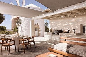Enjoy a relaxed dining experience in this serene outdoor space with a round table and comfortable seating.