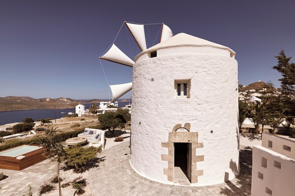 Traditional windmill stands amidst serene waters and a paved walkway.