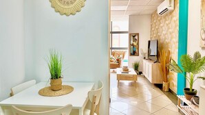 A modern living room with a dining area, featuring a clock, a TV, and a large window. - VALEANA (Málaga)