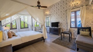 A bedroom with a canopy bed, a sofa, a TV, and a small table. - Echor Reis Magos Villa Goa (Verem)