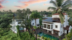 A modern house with a pool, surrounded by lush greenery and palm trees. - Echor Reis Magos Villa Goa (Verem)