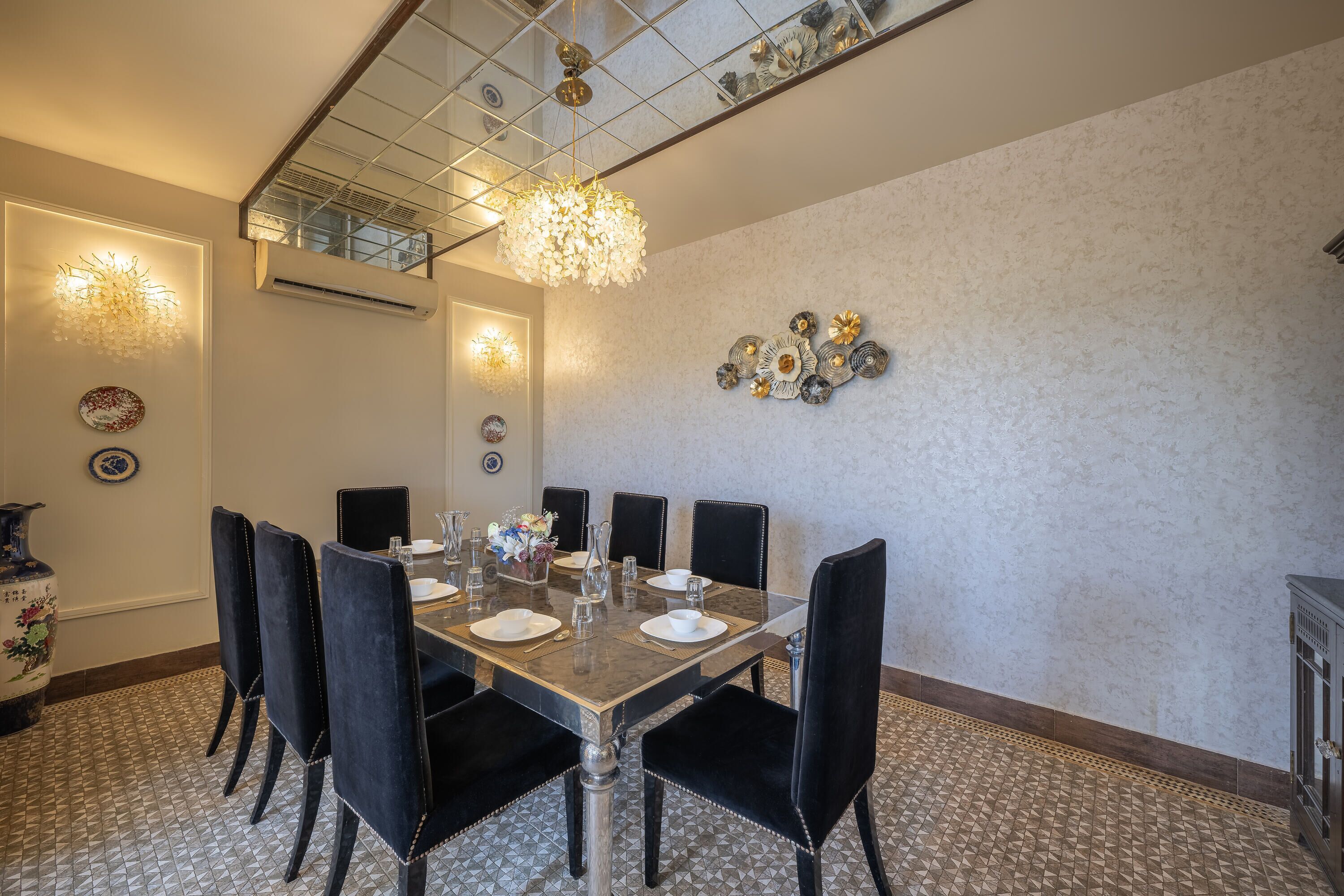 A dining area with a rectangular table set for six, surrounded by black upholstered chairs.