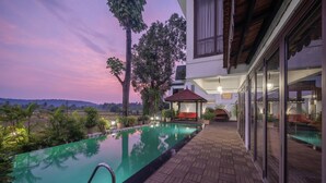 An infinity pool with a wooden deck, surrounded by potted plants and a gazebo. - Echor Reis Magos Villa Goa (Verem)