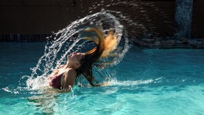 Iemand in een zwembad, omringd door opspattend water.