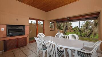 Enjoy meals in this dining area with a table and six chairs, surrounded by a lush garden view.