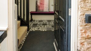 A hallway with a patterned floor, a bench, and a staircase. - No 1 @ The Rocket Rooms Apartments (Berwick-upon-Tweed)