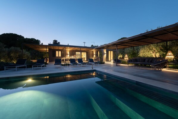 A modern outdoor pool area with lounge chairs and a covered seating area.